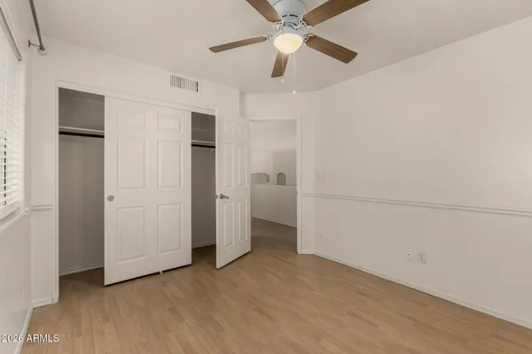 an empty room with closet and a ceiling fan