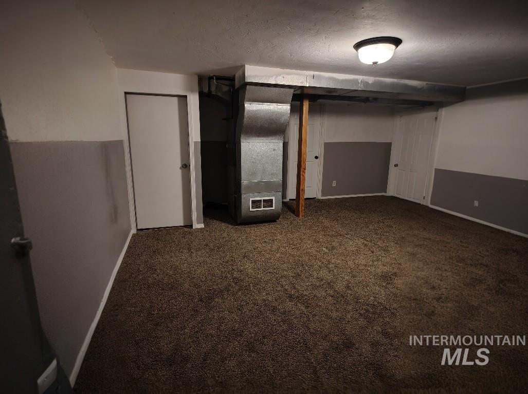 820 Meadows Drive Twin Falls, ID 83301 - Photo 14 of 23 Finished basement with dark carpet, heating unit, and a textured ceiling