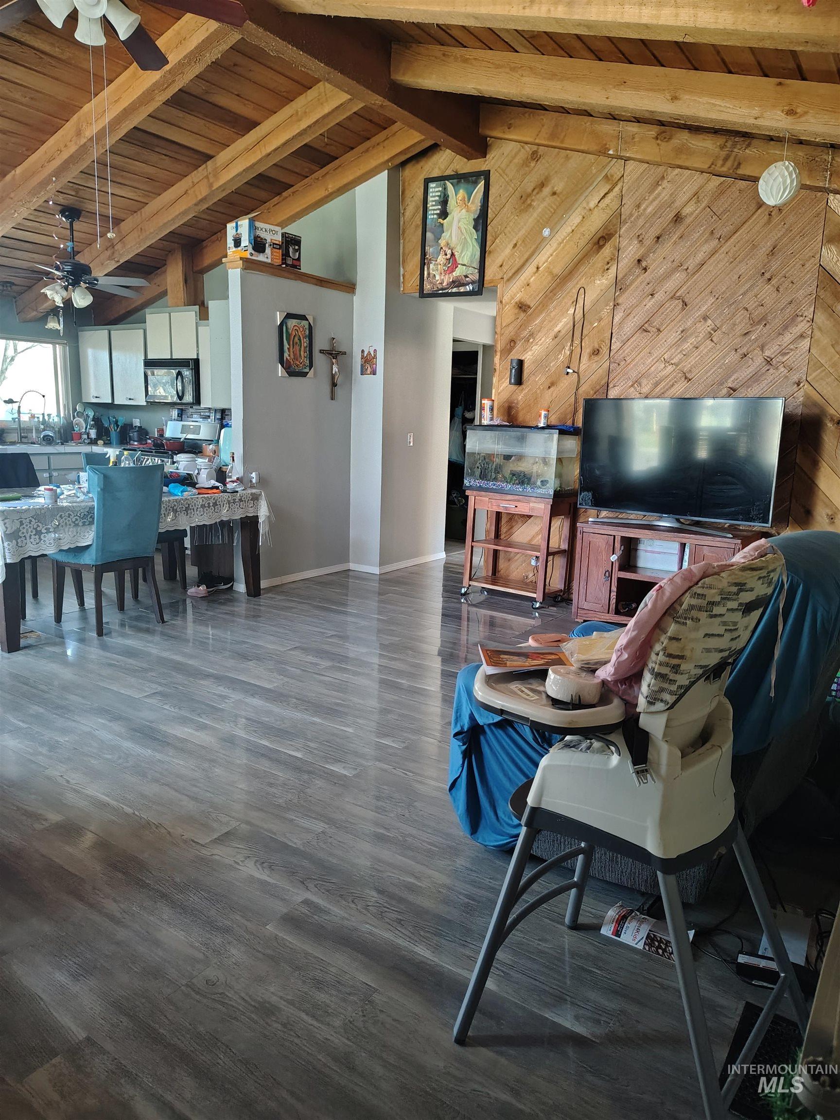 820 Meadows Drive Twin Falls, ID 83301 - Photo 18 of 18 Living room featuring a ceiling fan, a high wooden beamed ceiling, wooden walls, and dark wood finished floors