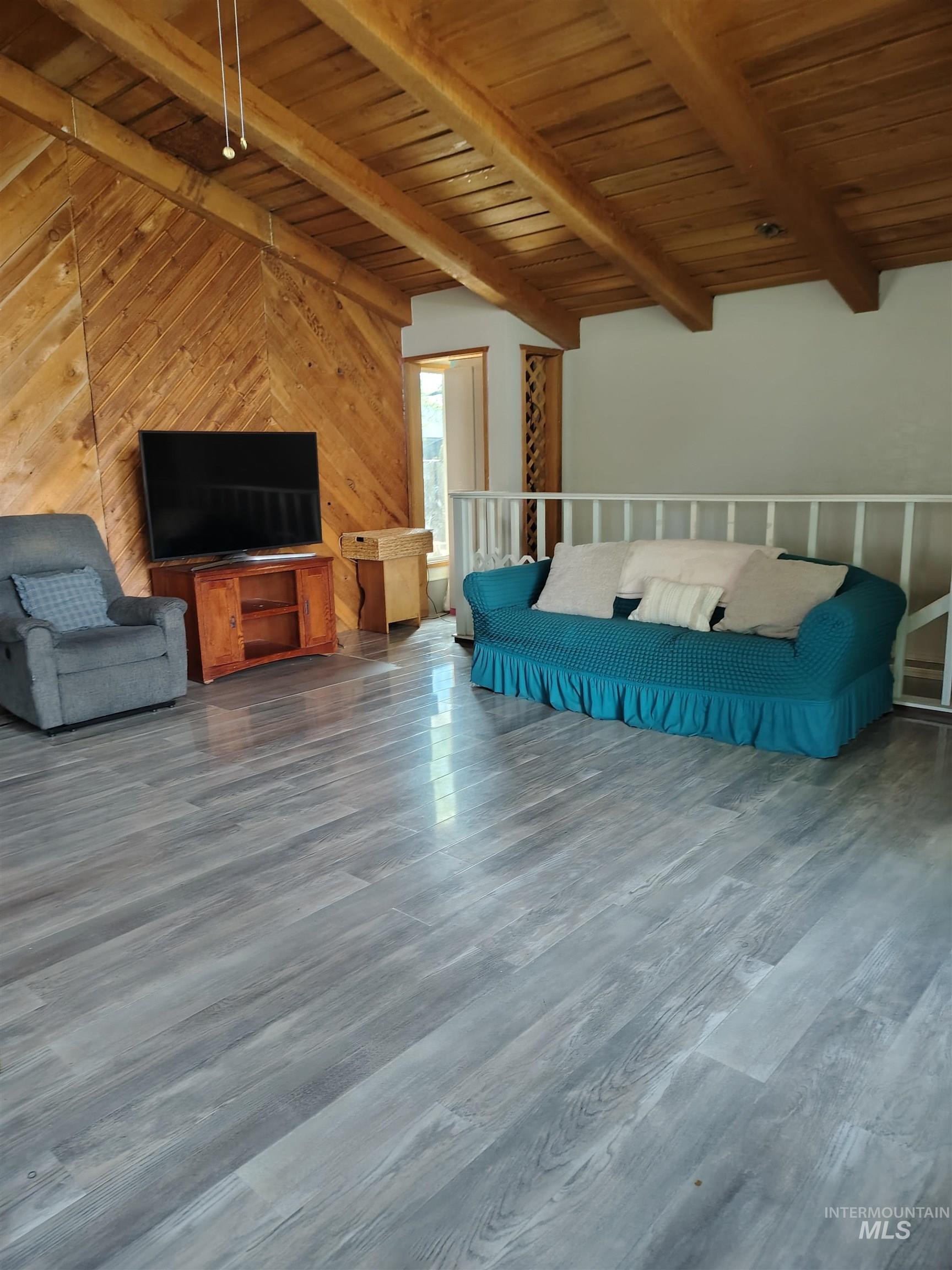 820 Meadows Drive Twin Falls, ID 83301 - Photo 3 of 23 Living room with a wooden ceiling with exposed beams, wooden walls, and wood finished floors