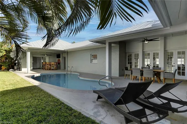 a view of a patio with table and chairs potted plants and floor to ceiling window