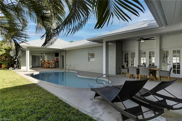 a view of a patio with table and chairs potted plants and floor to ceiling window