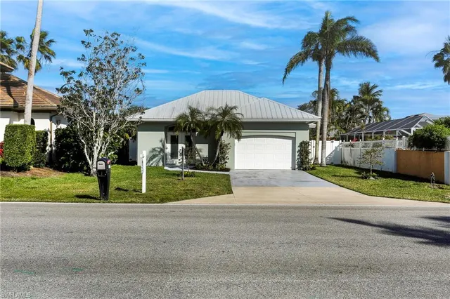 a view of a house next to a yard and palm trees