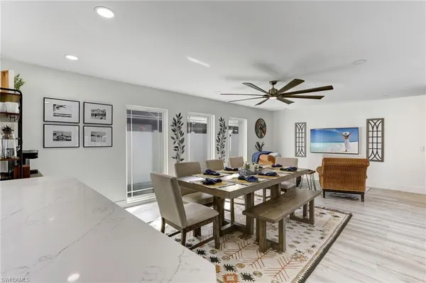 a dining room with wooden floor a chandelier fan a wooden table and chairs