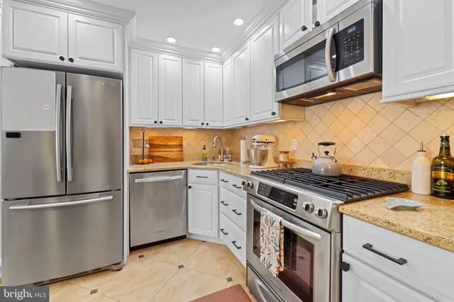 a kitchen with stainless steel appliances granite countertop a stove a refrigerator and a microwave