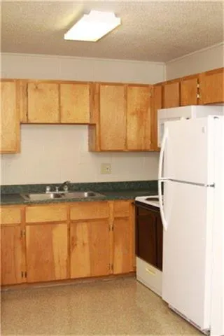 a kitchen with stainless steel appliances granite countertop a refrigerator a stove and a sink with wooden floors