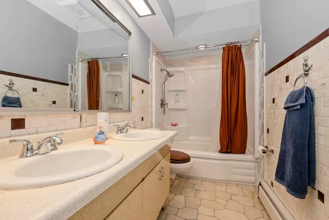 a bathroom with a sink a toilet a mirror and shower