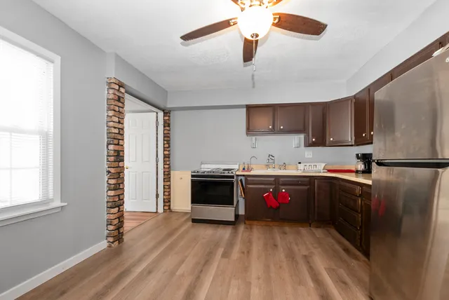 a kitchen with stainless steel appliances granite countertop a refrigerator a sink dishwasher a stove and a refrigerator with wooden floor