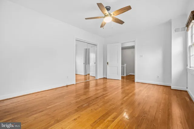 an empty room with wooden floor and a ceiling fan