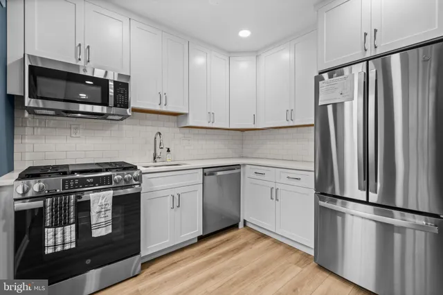 a kitchen with white cabinets and stainless steel appliances