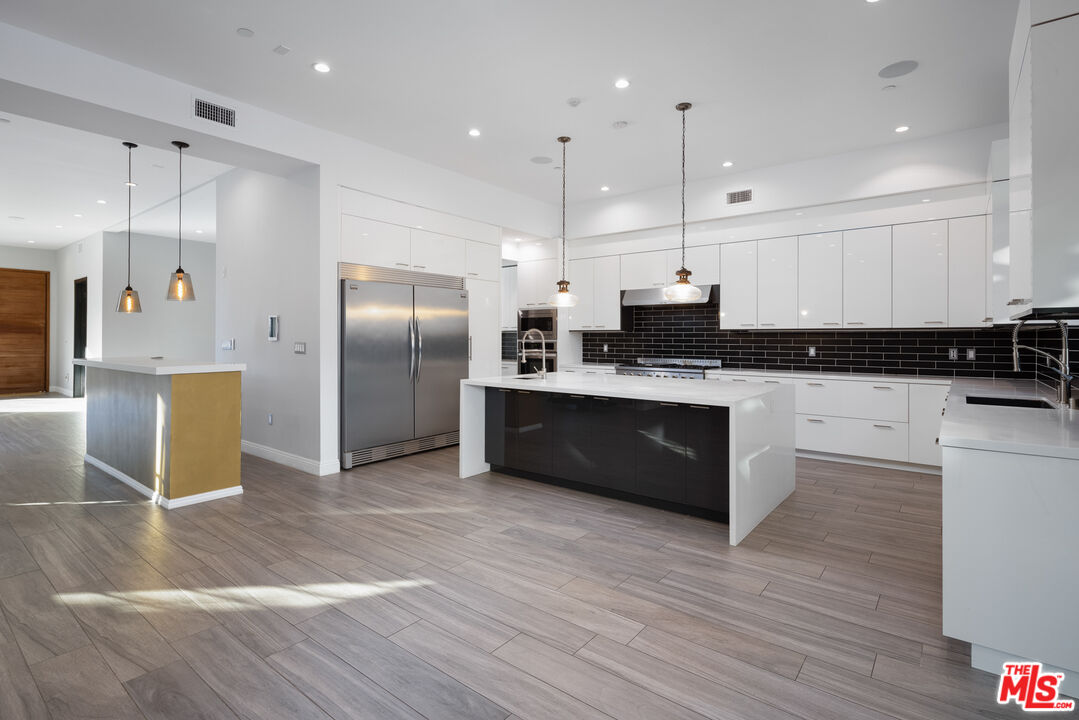 156 North Wetherly Drive Beverly Hills, CA 90211 - Photo 13 of 57 a kitchen with stainless steel appliances kitchen island granite countertop a refrigerator a sink a stove a oven with wooden floor and cabinets