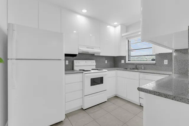 a kitchen with granite countertop white cabinets and white appliances