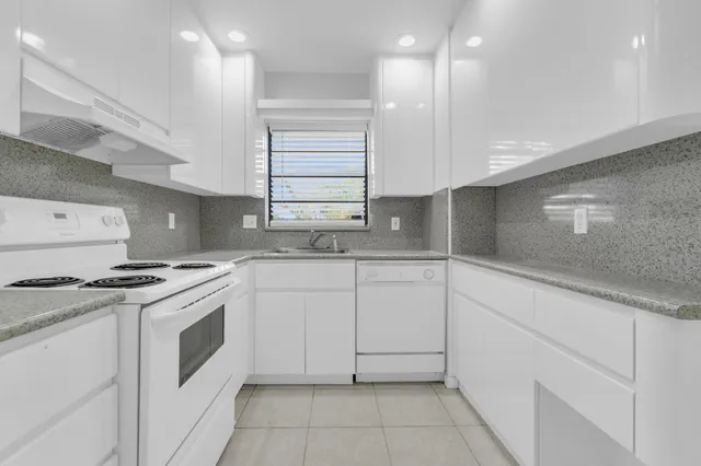 a kitchen with granite countertop white cabinets and white appliances