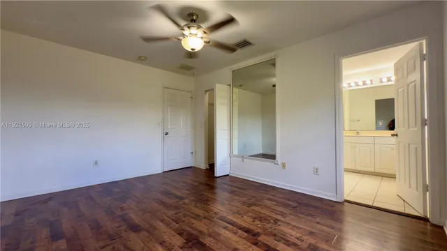 an empty room with wooden floor and ceiling fan