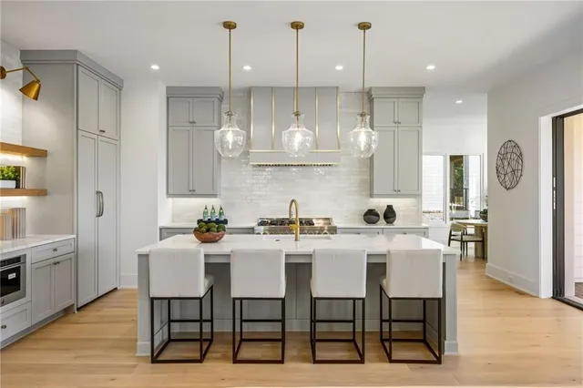a kitchen with stainless steel appliances kitchen island granite countertop a dining table chairs and white cabinets