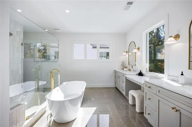 a bathroom with a double vanity sink and mirror with bathtub