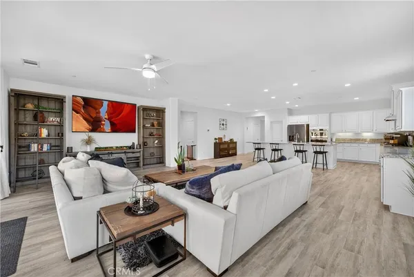a living room with furniture kitchen view and a wooden floor