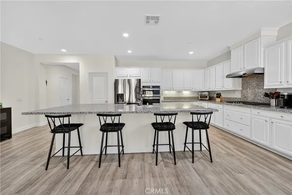 a kitchen with stainless steel appliances a table chairs refrigerator and cabinets