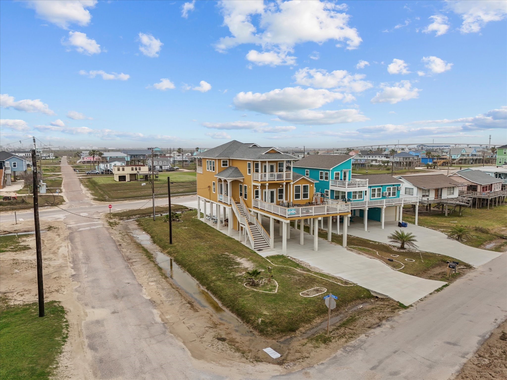 1018 Seashell Drive Surfside Beach, TX 77541 - Photo 7 of 49 This elevated coastal home features vibrant exterior colors, expansive balconies, and a spacious driveway. It's situated on a corner lot with nearby beach access and offers stunning views of the surrounding neighborhood.