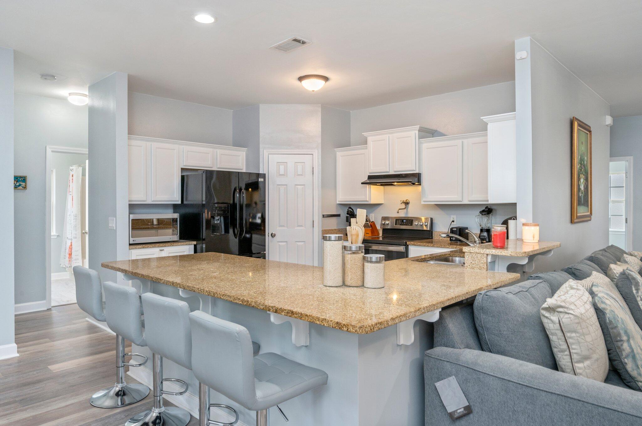 6082 Robin Road Crestview, FL 32539 - Photo 11 of 45 a kitchen with stainless steel appliances granite countertop a stove top oven a sink dishwasher and white cabinets with wooden floor