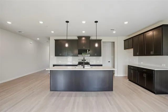 a large kitchen with stainless steel appliances kitchen island granite countertop a large counter top and wooden floors