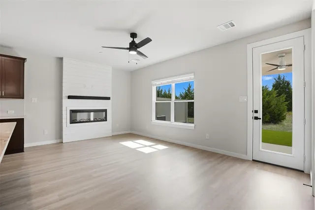 a view of an empty room with a window and wooden floor