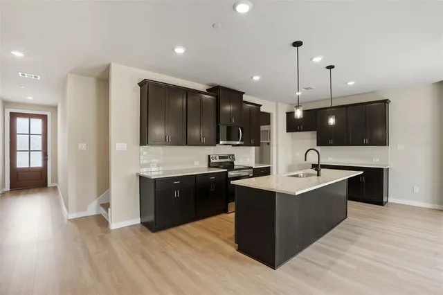 a large kitchen with stainless steel appliances a large counter top and wooden floor