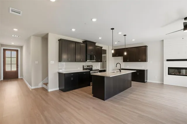 a large kitchen with stainless steel appliances a large counter top and a wooden floors