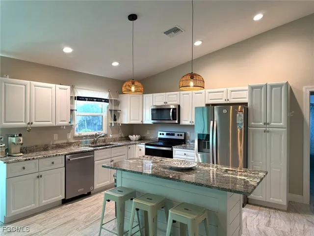 a kitchen with stainless steel appliances granite countertop a sink refrigerator and cabinets