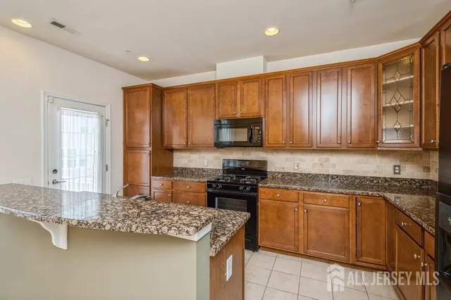 a kitchen with kitchen island granite countertop a sink stove and cabinets