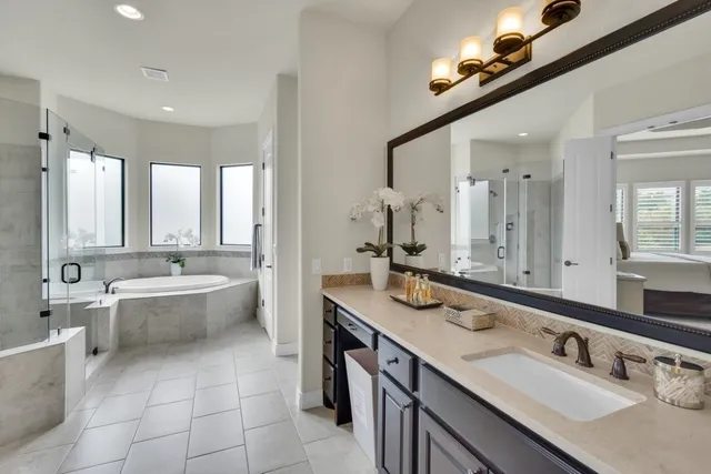 a bathroom with a double vanity sink large mirror and a bathtub