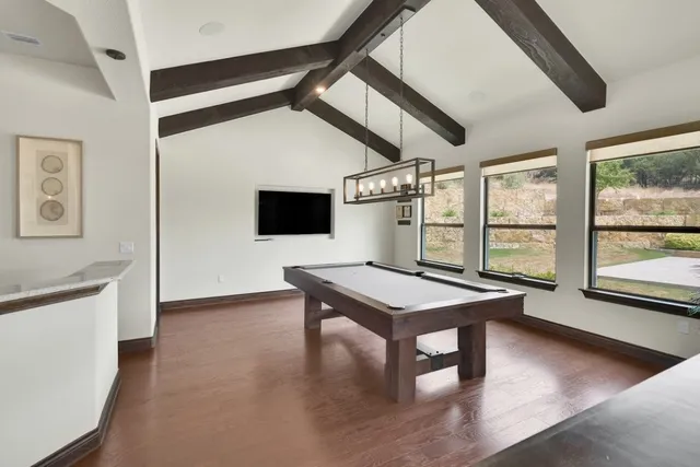 a room with furniture pool table wooden floor and windows