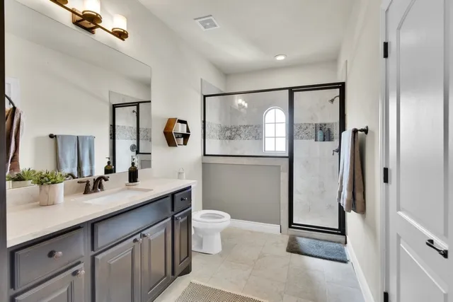 a spacious bathroom with a double vanity sink toilet mirror and shower