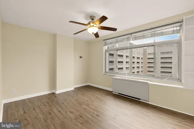 a view of an empty room with window and wooden floor