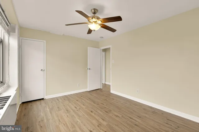 an empty room with wooden floor and ceiling fan