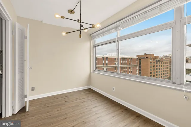 a view of an empty room with a window and wooden floor