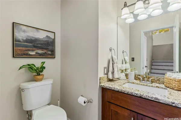 a bathroom with a granite countertop toilet sink and mirror