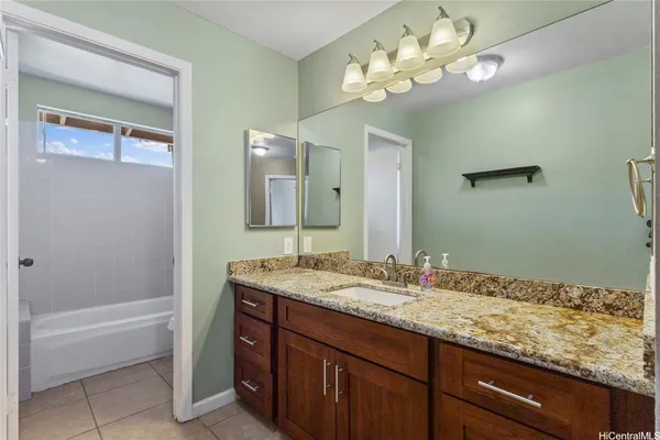 a bathroom with a granite countertop sink a large mirror and a bath tub