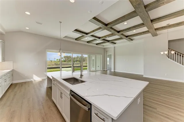 a view of a kitchen with kitchen island a counter tops pace a sink appliances and a large window