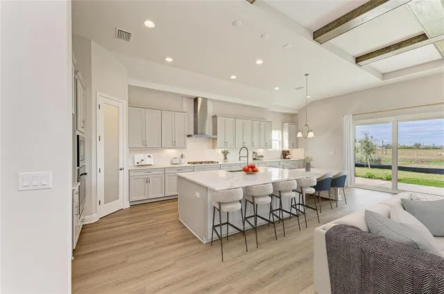 a large white kitchen with lots of counter space a sink appliances and cabinets