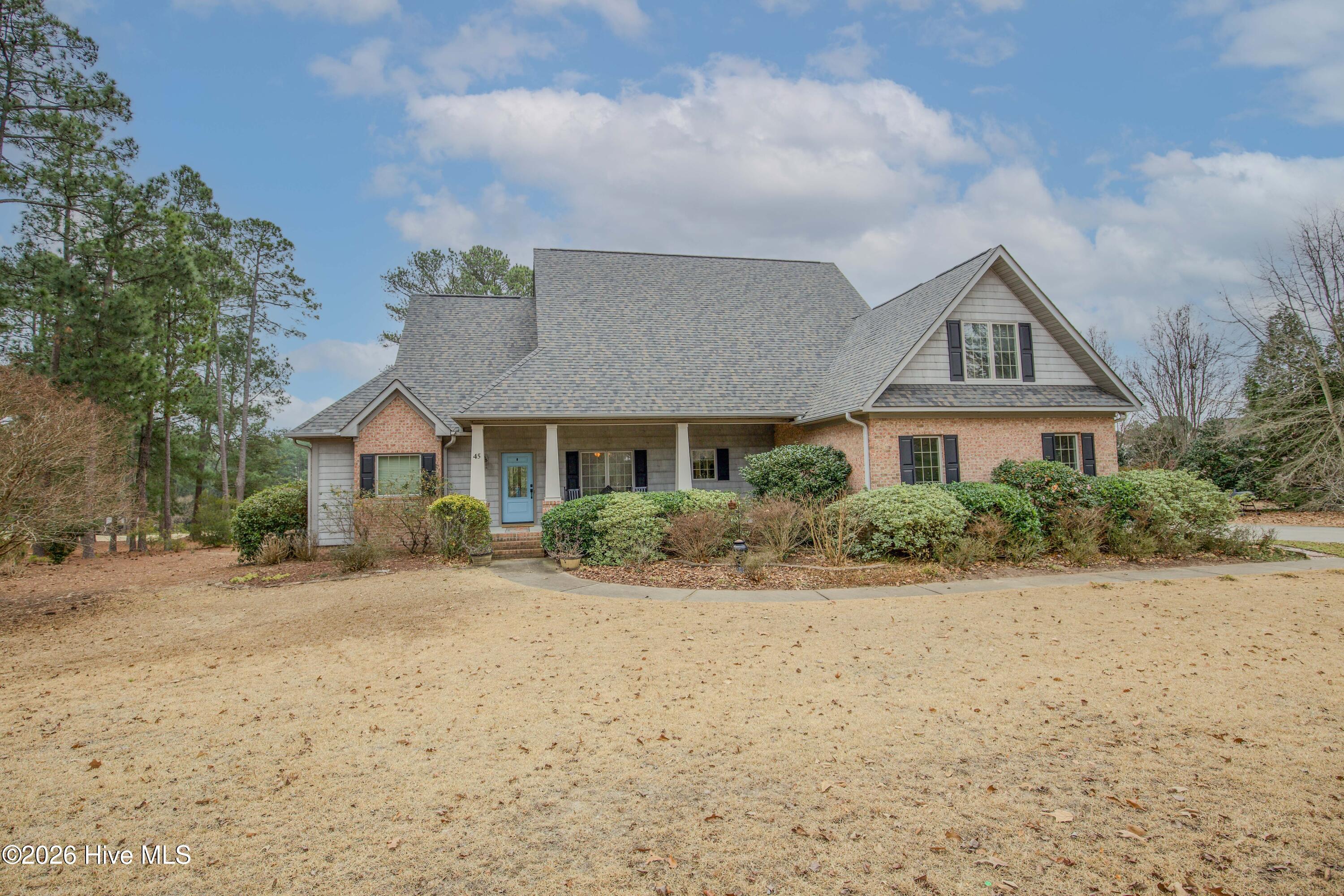 45 Richmond Road Jackson Springs, NC 27281 - Photo 1 of 93 A welcoming view of the front porch and bright blue door at 45 Richmond Rd, framed by manicured landscaping. The home's brand new architectural shingle roof adds to its curb appeal and long-term value. With classic brick, shake siding, and a wide front porch, this golf-front property combines charm and quality.