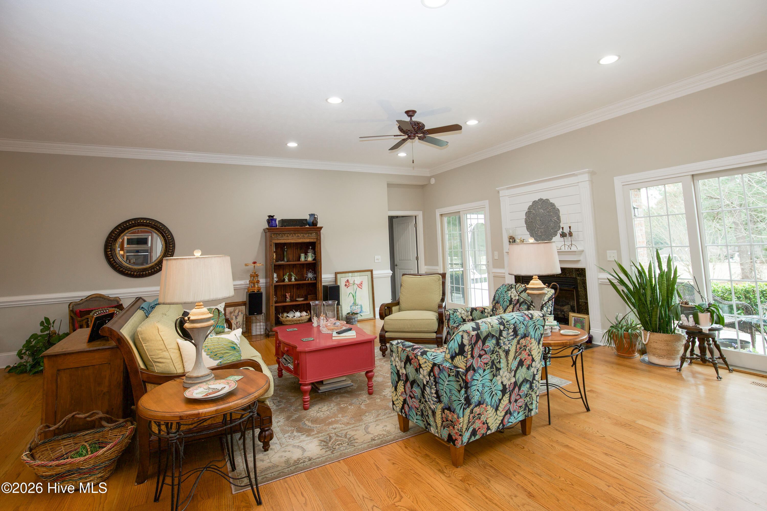 45 Richmond Road Jackson Springs, NC 27281 - Photo 13 of 93 Welcome to the bright and welcoming living room at 45 Richmond Rd in Jackson Springs, NC, located in the desirable Foxfire community. This elegant space features gleaming hardwood floors, crown molding, recessed lighting, and a cozy gas fireplace with a custom mantel. Expansive windows and French doors allow for abundant natural light and easy access to the outdoor patio. Perfect for relaxing or entertaining, this open-concept living area blends comfort with style in a beautifully maintained home.