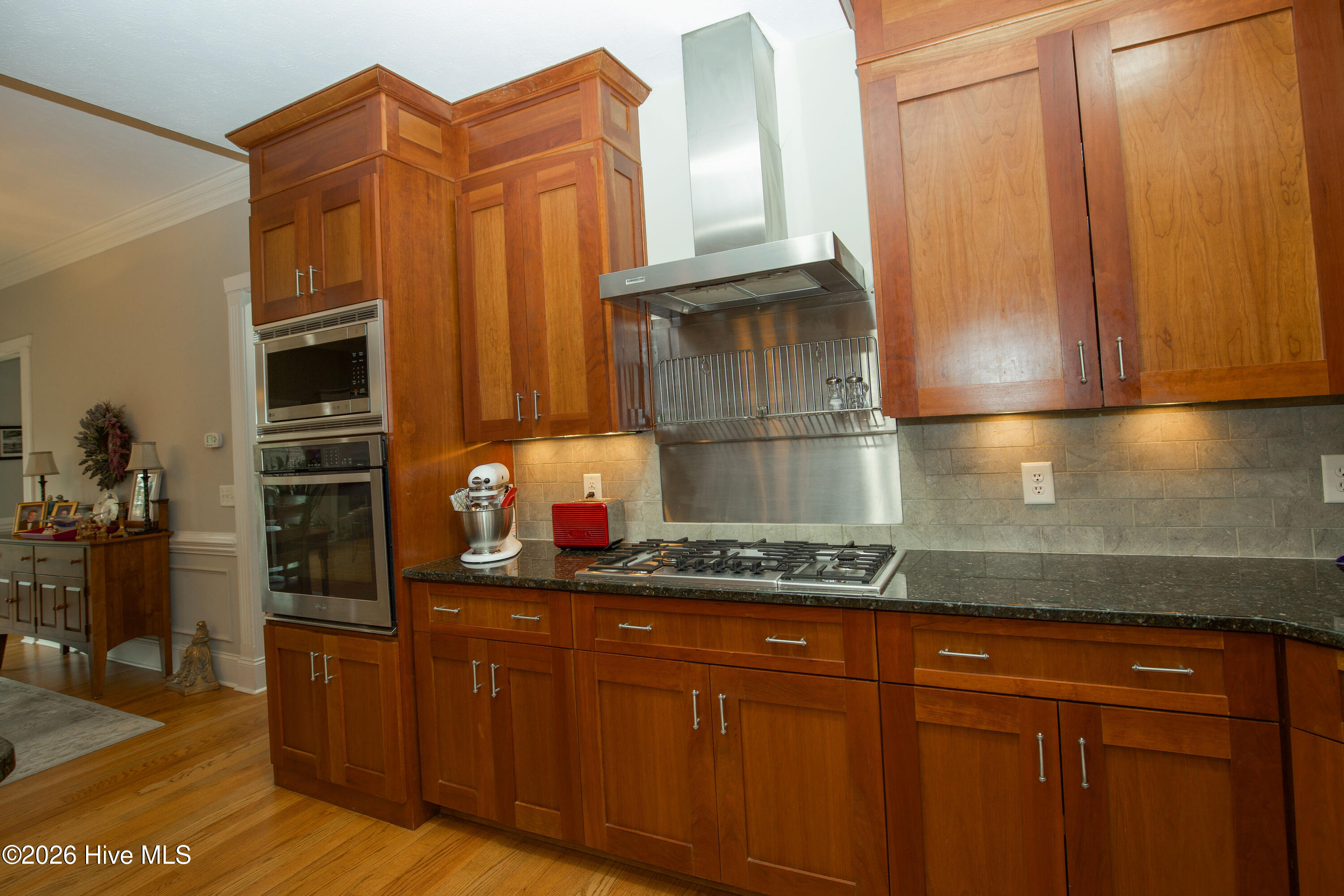 45 Richmond Road Jackson Springs, NC 27281 - Photo 20 of 93 Gourmet kitchen at 45 Richmond Rd featuring a premium stainless steel gas cooktop, wall oven, and built-in microwave. Rich custom cabinetry, granite countertops, and under-cabinet lighting create an elegant and functional culinary space ideal for everyday meals and entertaining.