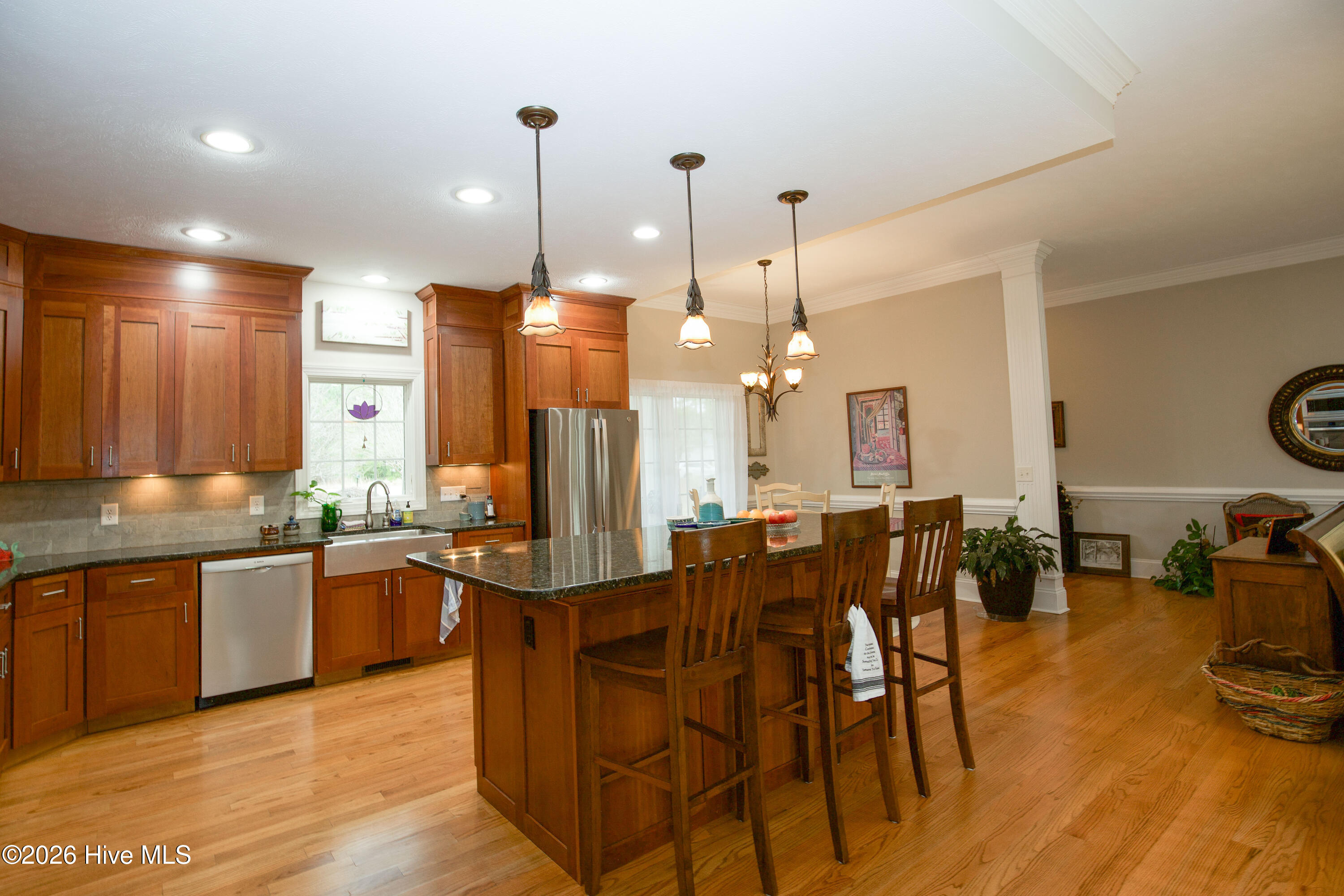 45 Richmond Road Jackson Springs, NC 27281 - Photo 23 of 93 Stunning kitchen at 45 Richmond Rd showcasing a large center island with granite countertops and pendant lighting, perfect for gatherings. Beautiful custom cabinetry, stainless steel appliances, and a farmhouse sink complete the space. The open concept flows into a light-filled dining area and beyond, offering great sightlines and spacious living.