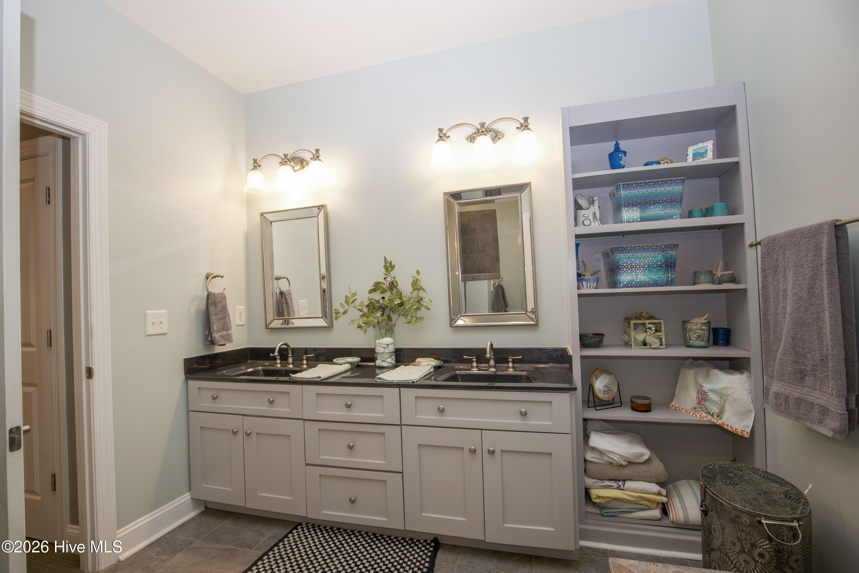45 Richmond Road Jackson Springs, NC 27281 - Photo 37 of 93 The primary bathroom at 45 Richmond Rd features a dual-sink vanity with granite countertops, elegant framed mirrors, and custom open shelving for stylish, functional storage, perfectly balancing convenience and charm.