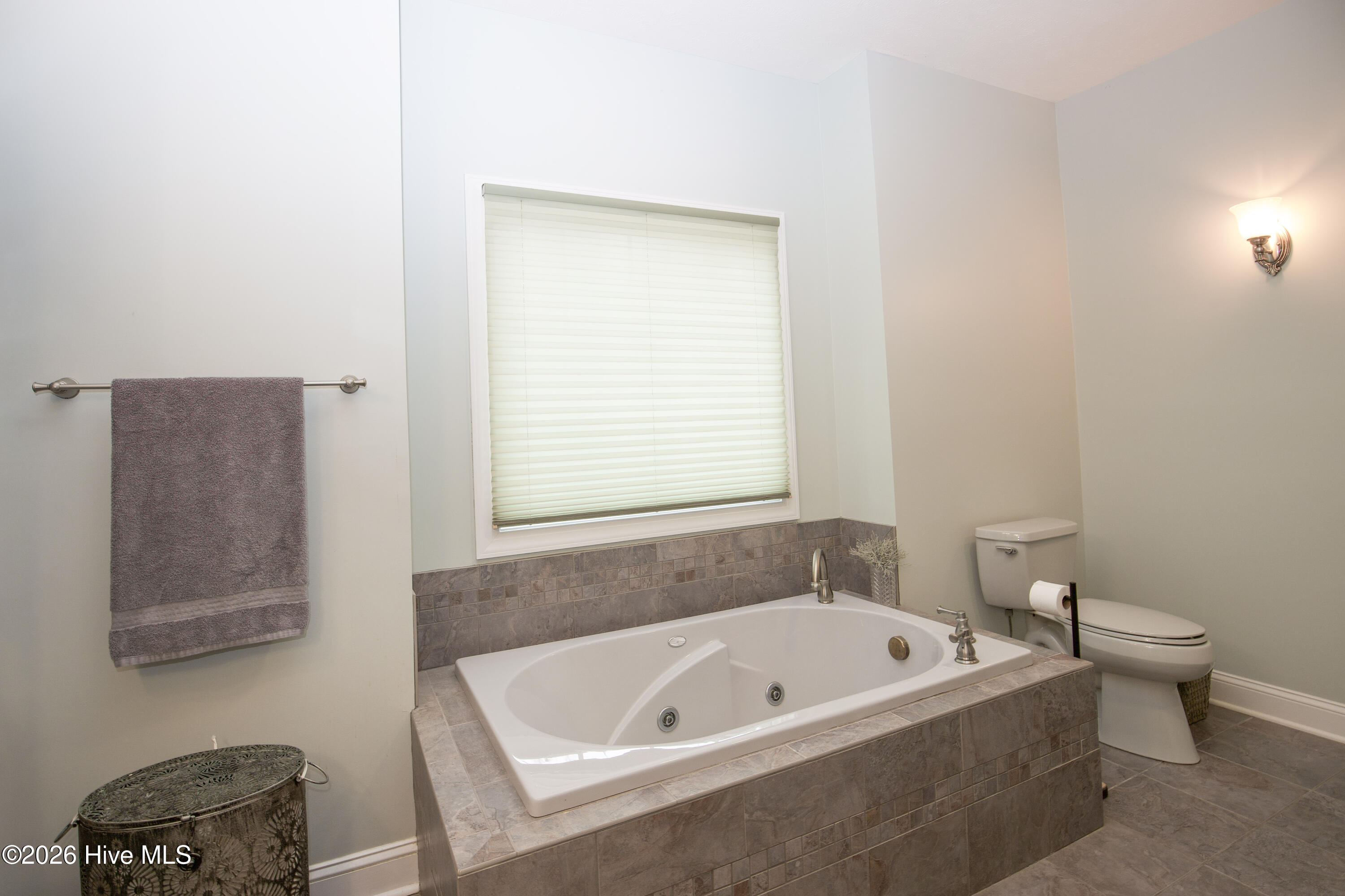 45 Richmond Road Jackson Springs, NC 27281 - Photo 39 of 93 Relax and unwind in the spa-like primary bathroom featuring a luxurious jetted soaking tub with custom tile surround. Natural light filters through the large window, creating a serene retreat just steps from the primary suite.