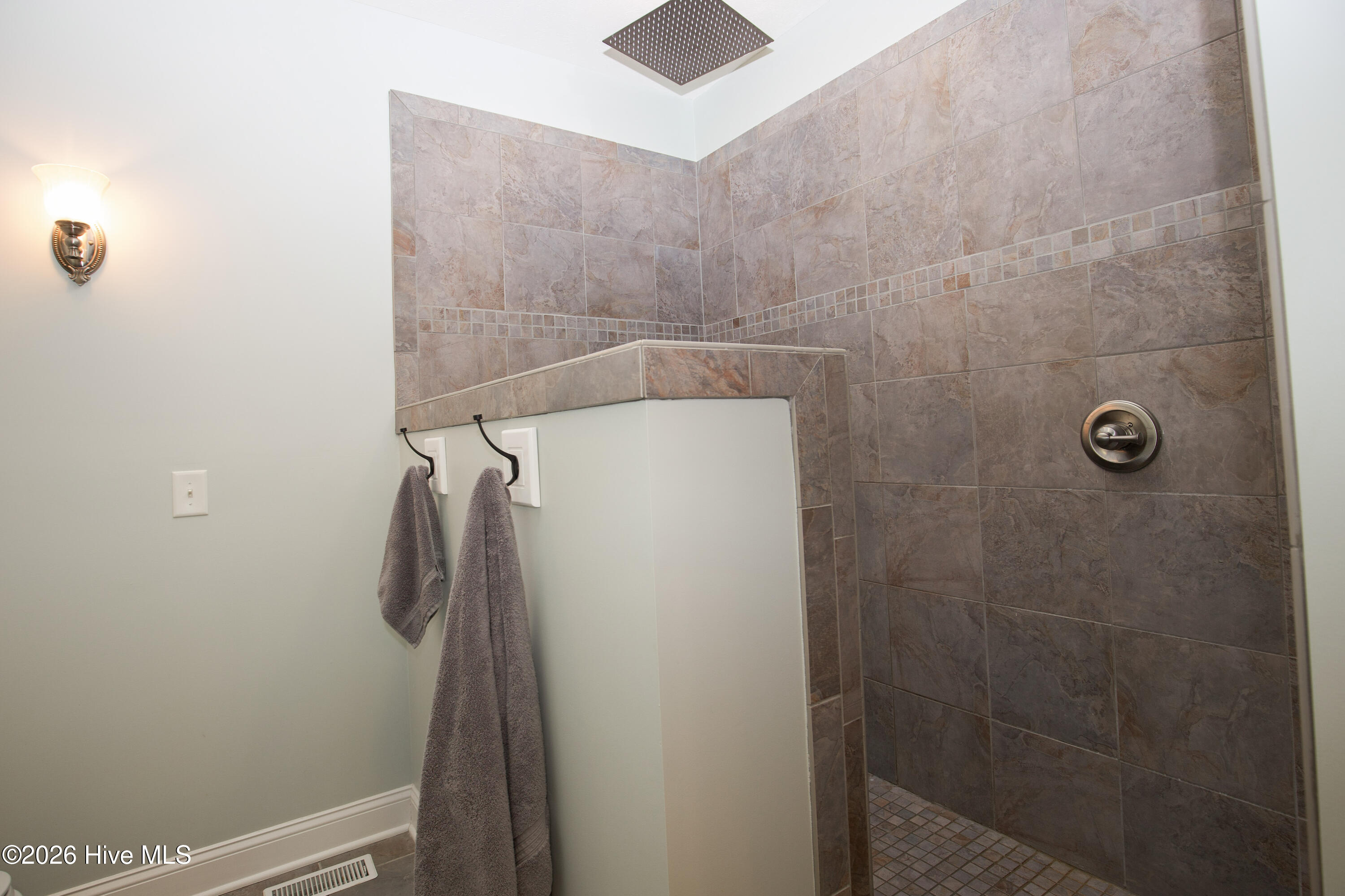 45 Richmond Road Jackson Springs, NC 27281 - Photo 41 of 93 At 45 Richmond Road, the primary suite offers a spa-like retreat with a beautifully designed walk-in shower. Featuring elegant tilework, a rainfall showerhead, and a sleek, open layout, this custom shower blends luxury with everyday convenience.