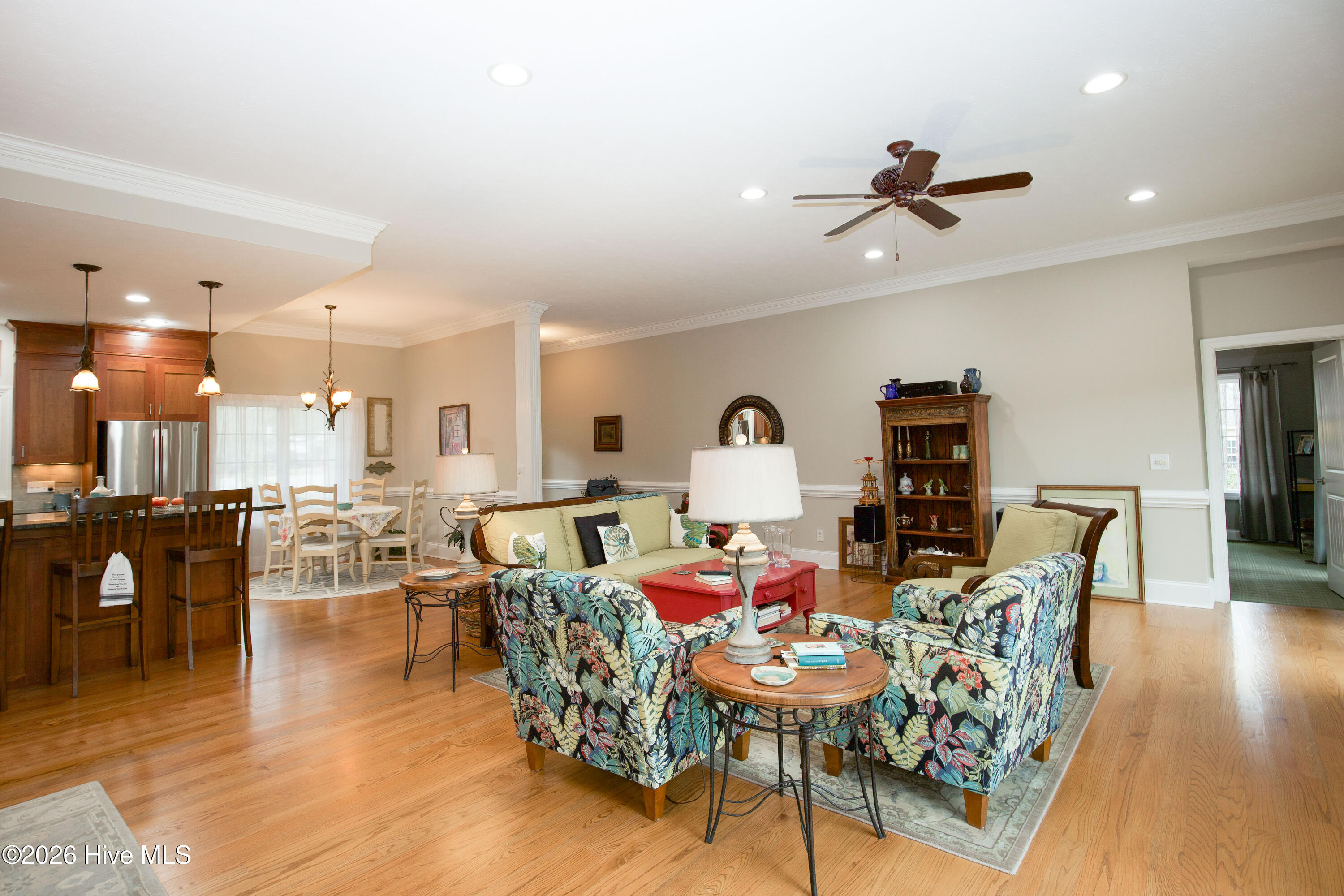 45 Richmond Road Jackson Springs, NC 27281 - Photo 46 of 93 This inviting open-concept living space seamlessly connects the living room, kitchen, and dining area, creating a perfect layout for both everyday living and entertaining. The room features gleaming hardwood floors, recessed lighting, crown molding, and large windows that fill the space with natural light. A ceiling fan adds comfort, while the bar seating at the kitchen island encourages casual dining and conversation. The adjacent dining nook offers a cozy setting for meals with a view of the backyard.