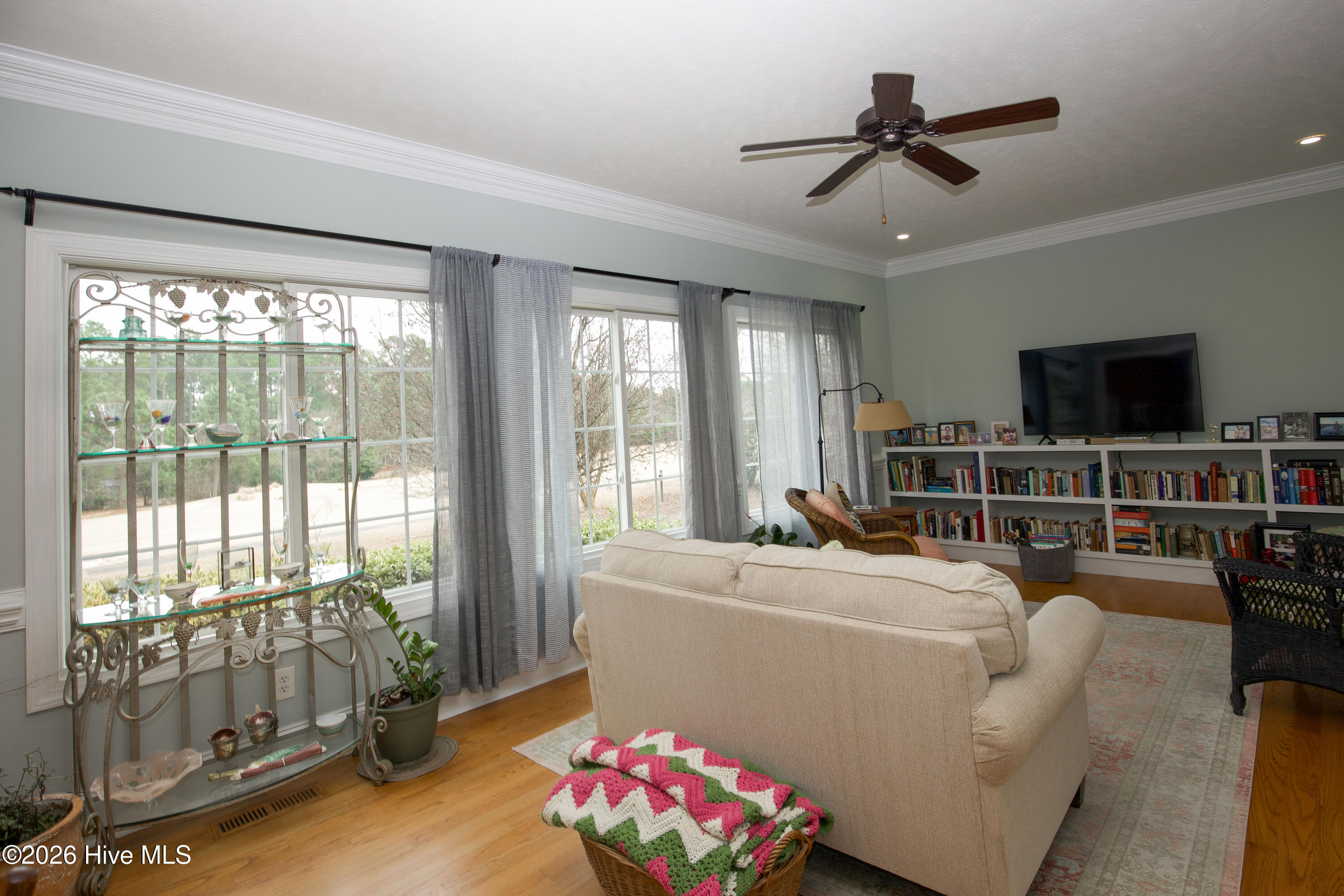 45 Richmond Road Jackson Springs, NC 27281 - Photo 50 of 93 The cozy study at 45 Richmond Road offers a warm and inviting space ideal for reading, relaxing, or casual gatherings. A wall of oversized windows brings in abundant natural light, while the built-in bookcases, hardwood floors, and crown molding add timeless charm. The room is centered around a comfortable seating area with a view of the TV, making it both functional and relaxing.