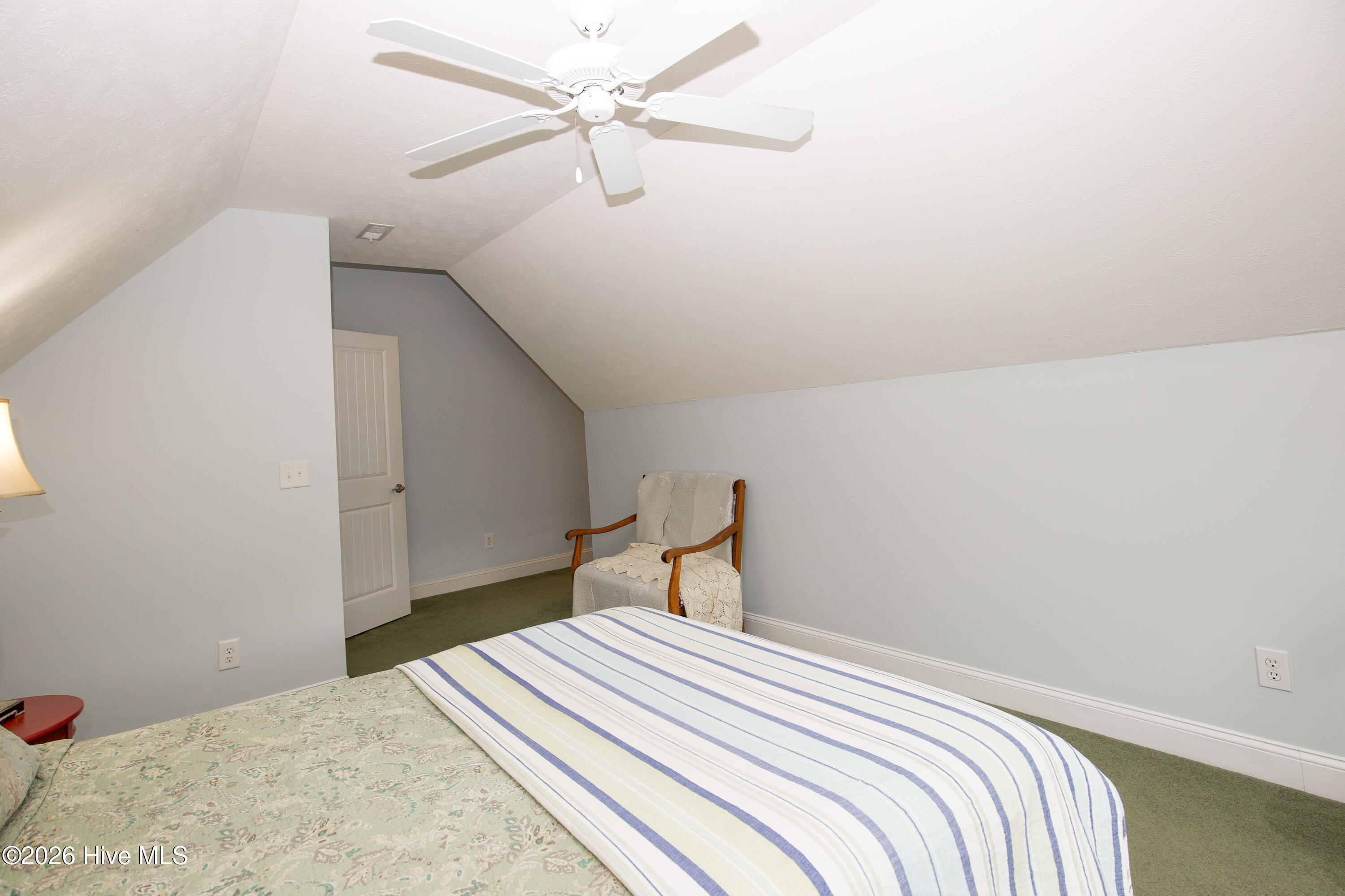 45 Richmond Road Jackson Springs, NC 27281 - Photo 59 of 93 Another view of the upstairs bedroom highlights its generous proportions and sloped ceiling architecture, creating a unique and serene retreat. A cozy reading nook fits perfectly beneath the angled wall, while soft lighting and a ceiling fan add comfort and practicality.